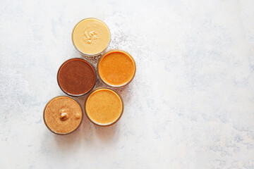 Homemade nuts butter in a glass jars with various nuts.