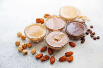 Homemade nuts butter in a glass jars with various nuts.