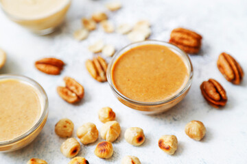 Homemade nuts butter in a glass jars with various nuts.