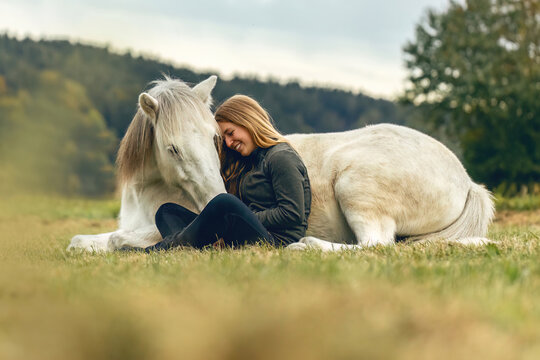 A young woman and her icelandic horse working and cuddle together, equestrian natural horsemanship concept