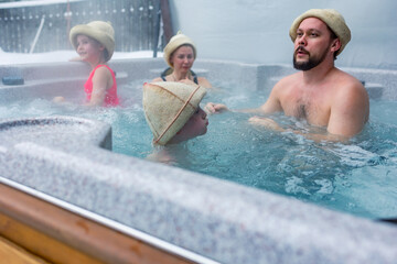 Cheerful happy family with children enjoys hot bath in jacuzzi whirlpool on cold winter day....