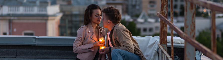 Private wedding for two in casual clothes on roof top with skyscrapers, urban cityscape on background. Romantic marriage proposal on Saint Valentine's Day. Happy loving beautiful young couple banner