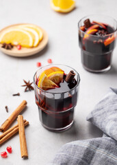 Fototapeta premium Mulled wine with orange, apple and cinnamon in glasses on a light background. The concept of a traditional winter hot drink