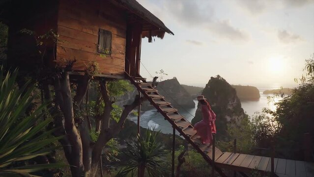 Woman walking up stairs home on tree at sunrise in Nusa Penida island, Bali in Indonesia.