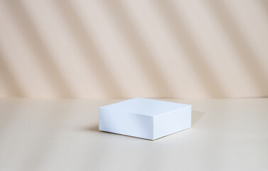 Abstract empty white box with shadows on a beige background. Layout concept for promotional product presentation, sale or cosmetics display.