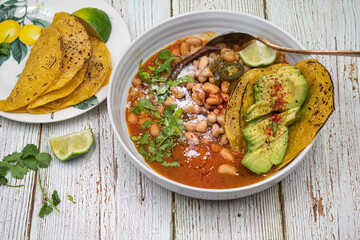 Vegan Mayocoba beans stew in spicy sauce with corn tacos and sliced avocado.