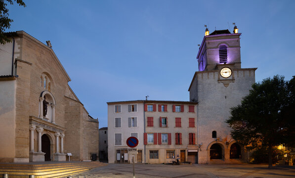 Twilight view of main square Place Mirabeau in city center of Pertuis with Church of Saint-Nicolas and medieval tower with clock, France.