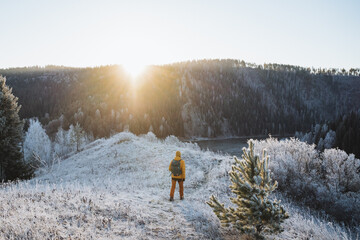 Hiker with backpack walking to meet the sun in the mountains, Sun glare shining at dawn of day,...