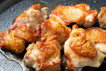 地鶏もも肉をフライパンでこんがり焼く調理シーン。
