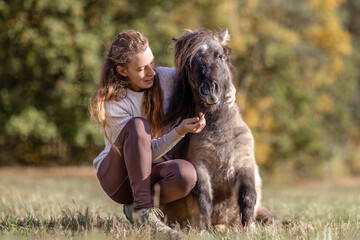 Natural Horsemanship concept: Cute portrait of a young woman and her pony working and interacting...