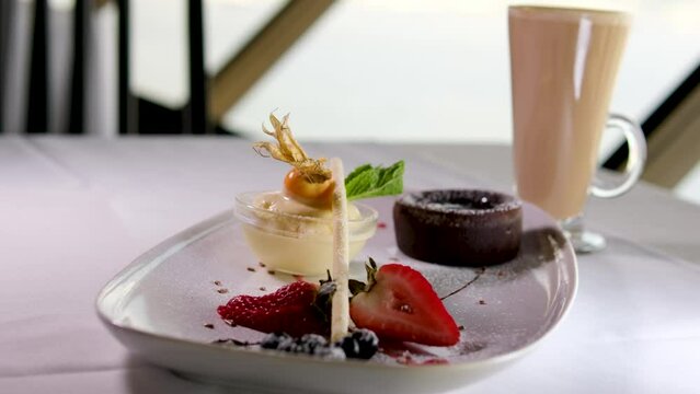 chocolate fondant on white plate with dark chocolate ice cream strawberries drops of syrup beautiful serving in an expensive restaurant. dessert food