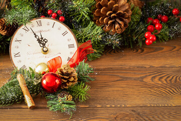New Year at midnight - Old clock with Christmas decorations, fir branches with pine cones, holiday...
