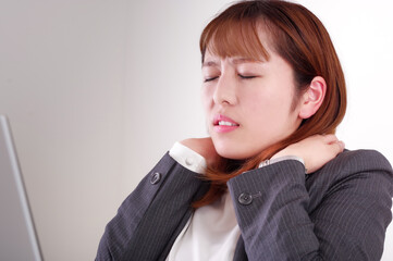 肩が痛そうに手を当てている女性