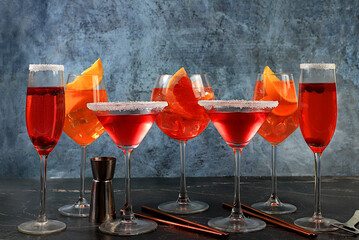 Assortment of alcoholic cocktail Aperol spritz, champagne and red martini in glasses on a dark...