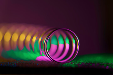 A multi-color, angular macro view of a  spring showing its spiral, tubular design.