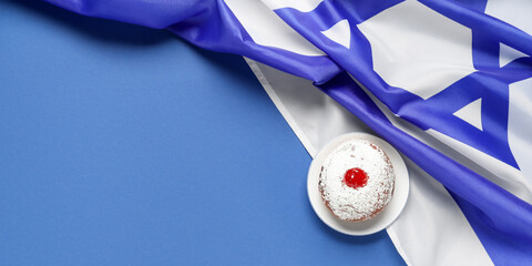 Traditional donut and flag of Israel on blue background with space for text. Hannukah celebration