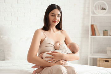 Young woman breastfeeding her baby in bedroom