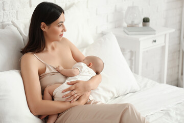Young woman breastfeeding her baby in bedroom