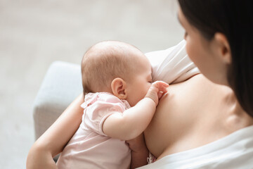 Young woman breastfeeding her baby at home, closeup