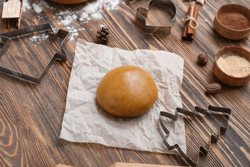 Composition with raw dough, spices and cutters for preparing Christmas cookies on wooden background