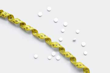 Measuring tape and pills on grey background