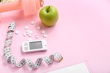 Glucometer, measuring tape, pills and apple on pink background