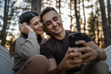 Man and woman young adult couple in nature listen music headphones