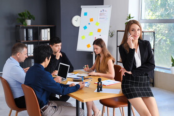 Young businesswoman talking by mobile phone in office