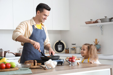 Cute little girl with her dad cooking in kitchen