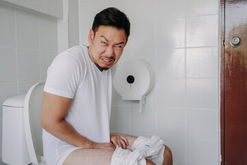 Funny face asian man pushing poop in the toilet as he has constipation.