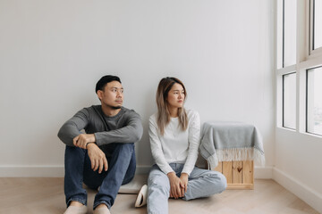 Boring and tired faces of asian lover sit on the floor of empty room. - obrazy, fototapety, plakaty