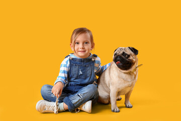 Little girl with cute pug dog on yellow background