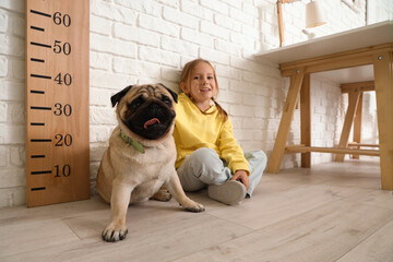 Little girl with cute pug dog at home