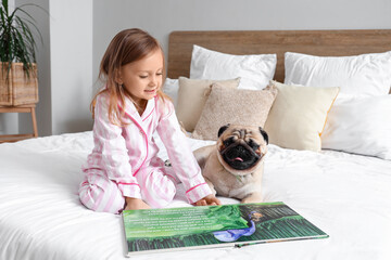 Little girl with cute pug dog and book in bedroom