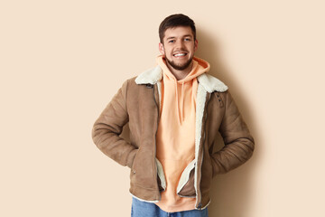 Young bearded man in sheepskin jacket on beige background