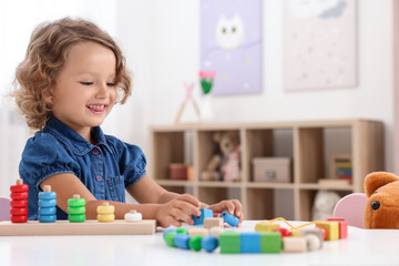 Motor skills development. Little girl playing with stacking and counting game at table indoors