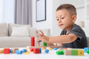 Motor skills development. Little boy playing with stacking and counting game at table indoors
