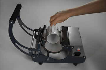Printing logo. Woman with mug using heat press at white table, closeup