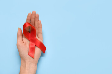 Woman with red ribbon on blue background. AIDS Day concept - obrazy, fototapety, plakaty