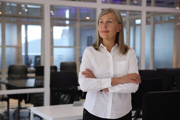 Smiling woman with crossed arms in office, space for text. Lawyer, businesswoman, accountant or...