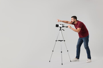 Excited astronomer with telescope pointing at something on light grey background. Space for text