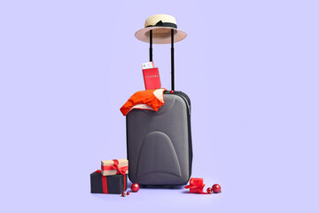Suitcase with beach accessories, passport and Christmas gift on color background