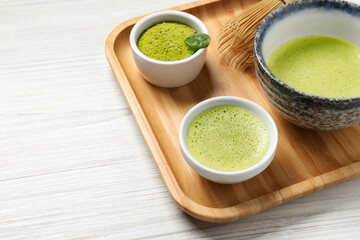 Fresh matcha tea, bamboo whisk and green powder on white wooden table, closeup. Space for text