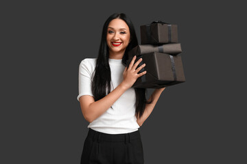 Beautiful stylish woman with gift boxes on dark background. Black Friday Sale