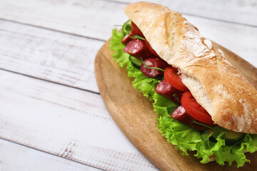 Delicious sandwich with sausages and vegetables on white wooden table, closeup. Space for text