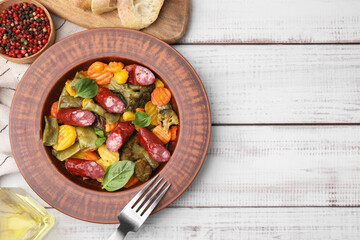 Delicious sausage and baked vegetables served on white wooden table, flat lay. Space for text