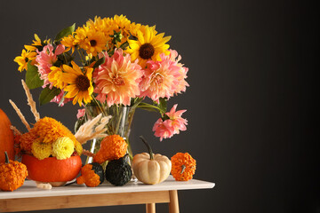 Autumn composition with beautiful flowers and pumpkins on white table against dark grey background. Space for text