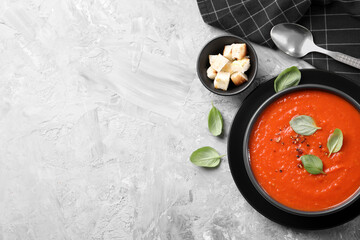 Delicious tomato cream soup served on grey textured table, flat lay. Space for text