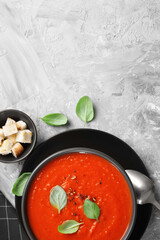 Delicious tomato cream soup served on grey textured table, flat lay. Space for text