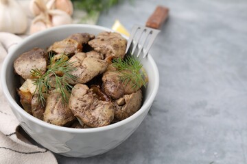 Tasty fried chicken liver with dill and fork on grey table, closeup. Space for text